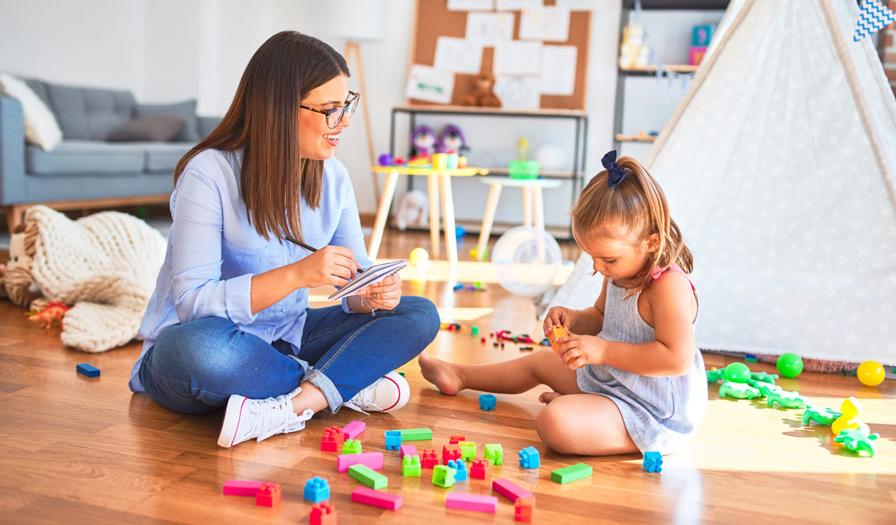 Young therapist woman speaking and treating child, counselor and behaviour correction at pedagogue payroom taking notes on clipboard